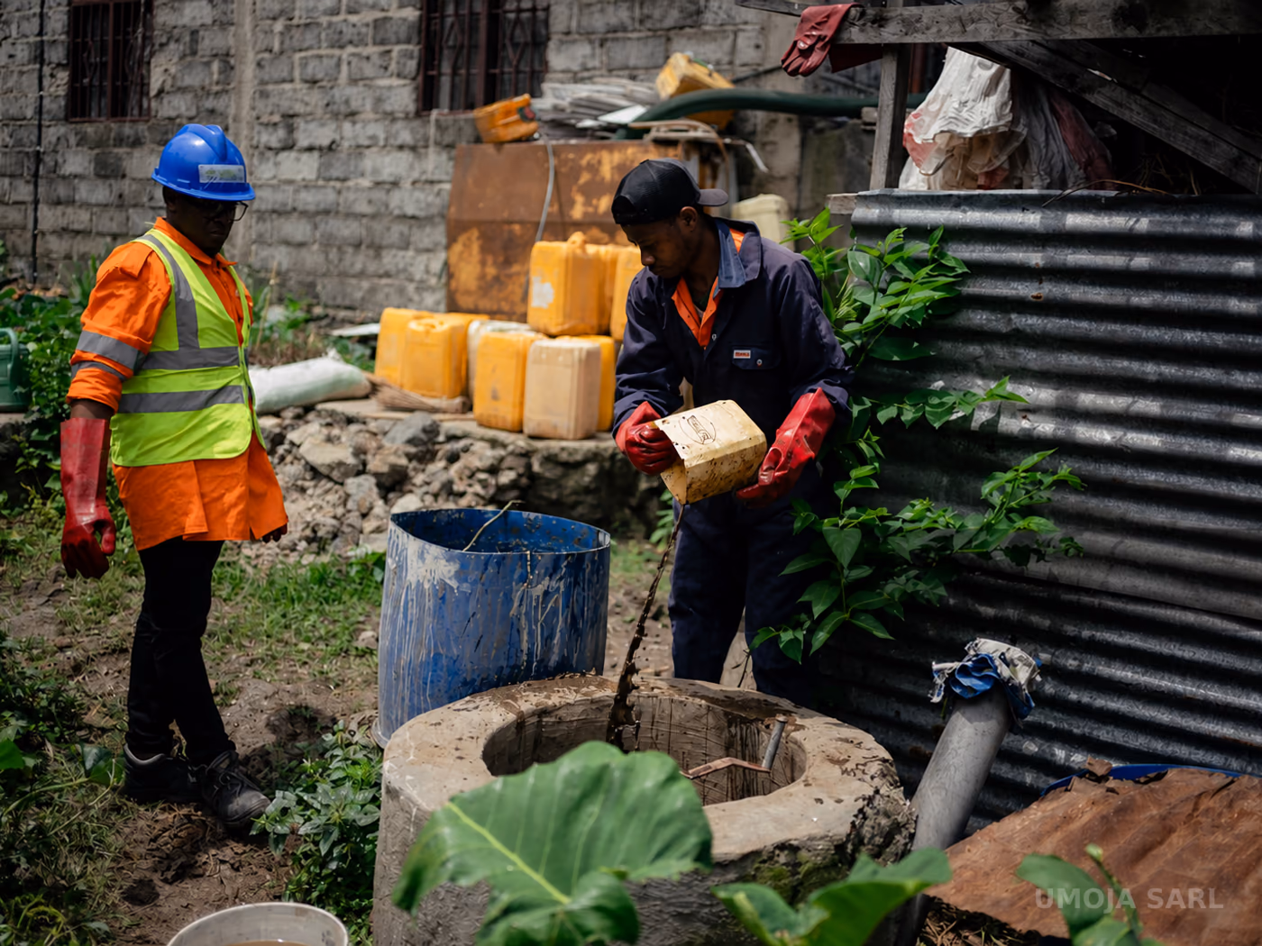 Techniciens UMOJA alimentant un ouvrage de biodigestion